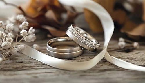 Elegant wedding rings adorned with delicate ribbon and floral ac
