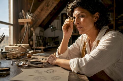 Woman examining gold signet ring at workbench