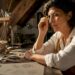 Woman examining gold signet ring at workbench