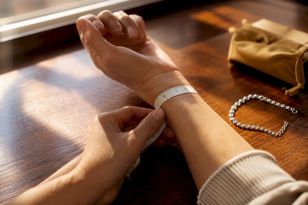Hands measuring wrist with cloth tape