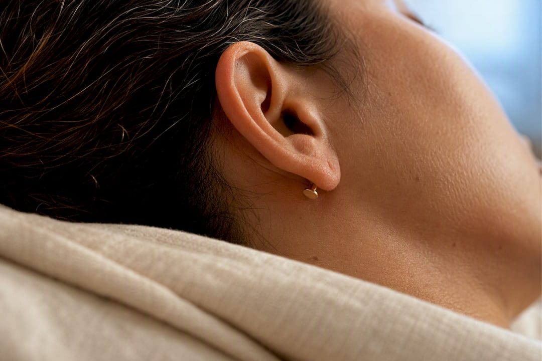 Flat earring back resting against linen pillow