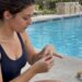 Woman removing a gold ring beside a pool
