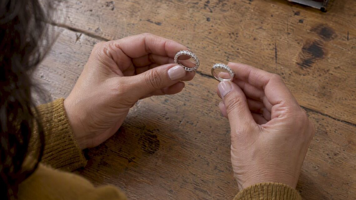 Hands comparing half and full eternity bands