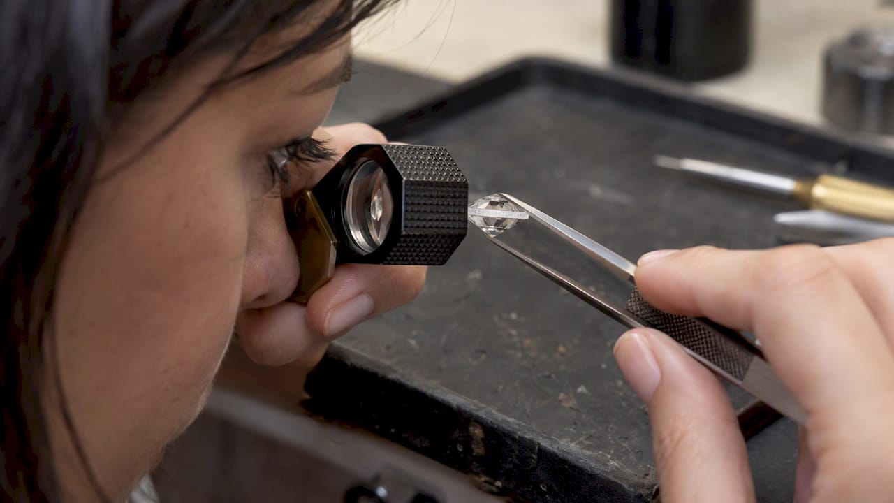 Loupe inspecting a diamond girdle inscription