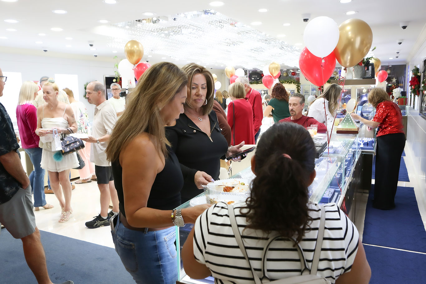 Two women being served appetizers at USA Jewels holiday open house