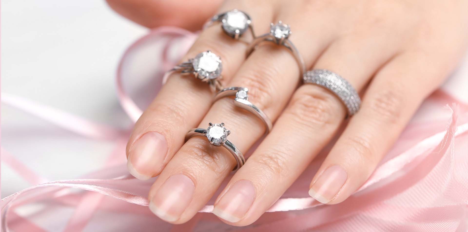 Womans hand wearing several styles of diamond rings and diamond bands: Telephone number 1-877-872-9909